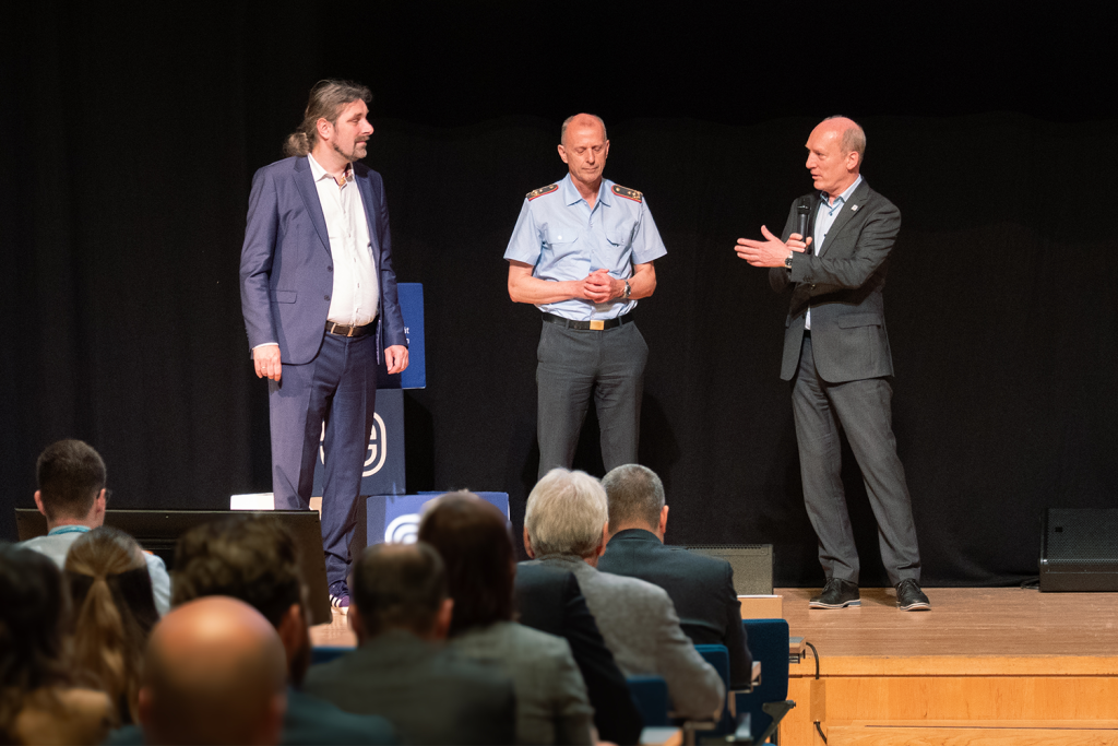 Eröffnung der SIC!2025: Prof. Dr. Christian Hummert, Generalmajor Jürgen Setzer und Wilfried Karl begrüßen die Teilnehmenden in Halle (Saale).